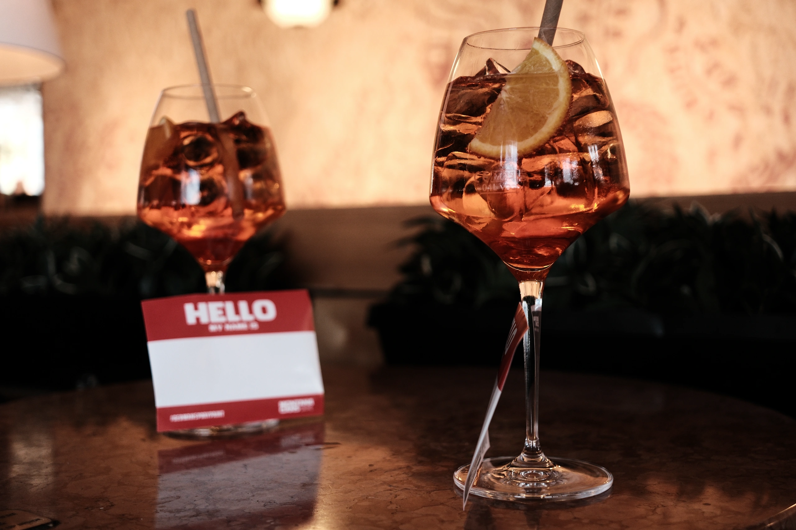 Two orange drinks beside a blank red hello name badge