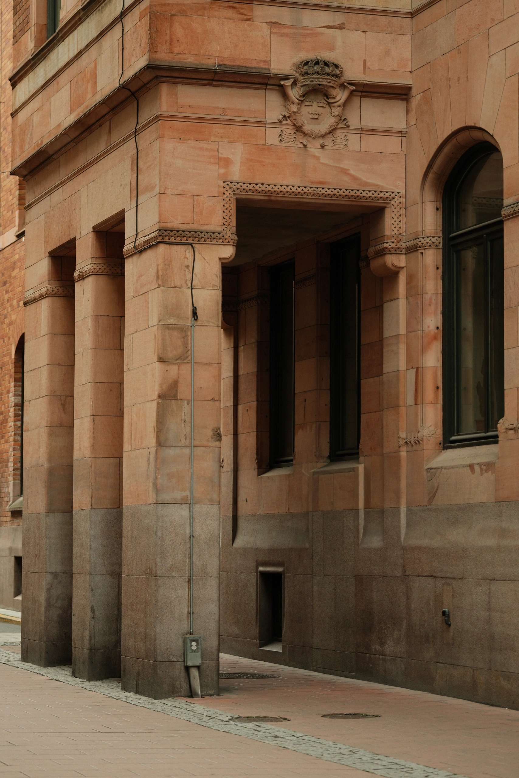 Stone building detail with a crowned globe carving above an arched passage