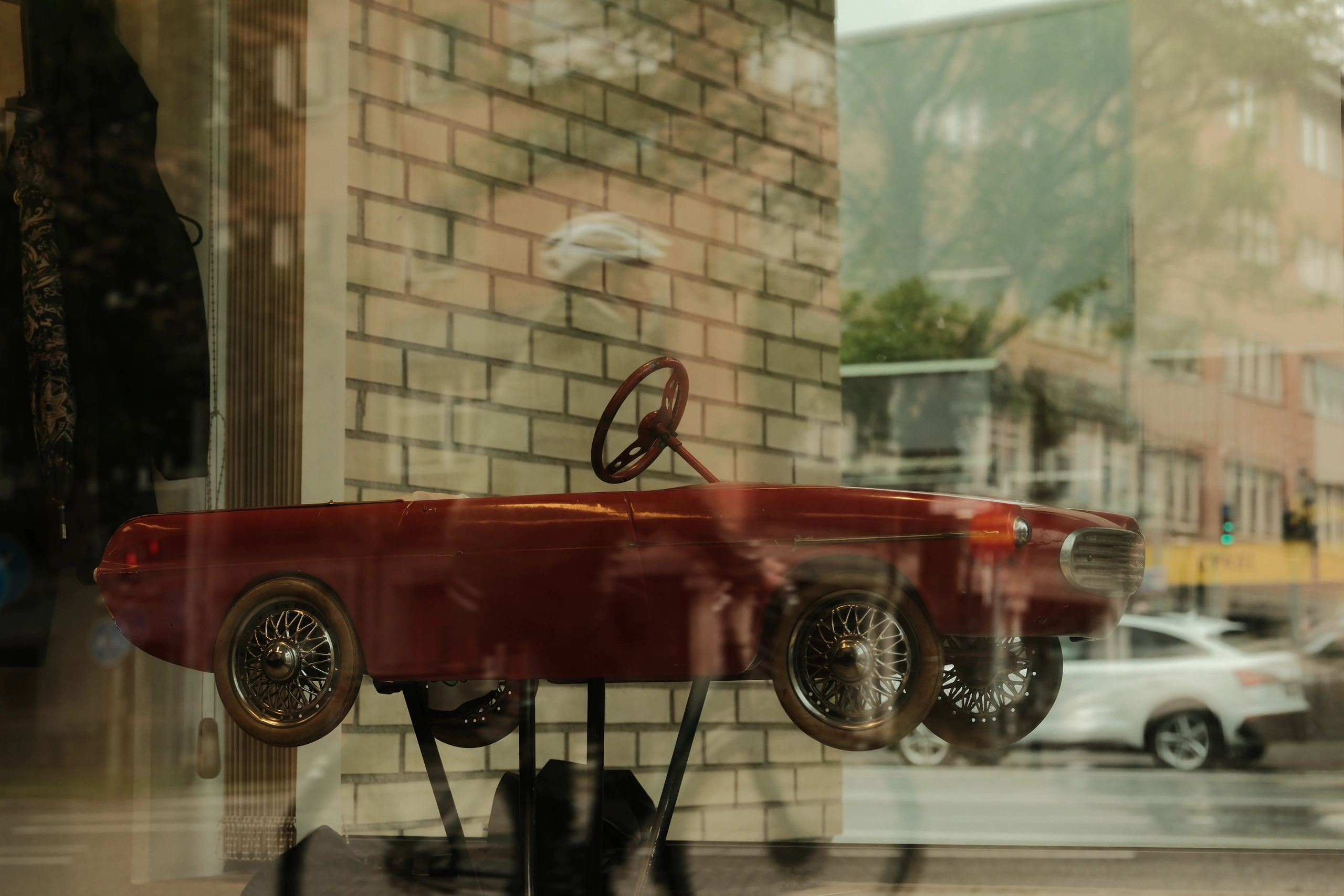 Red model car displayed behind a reflective shop window