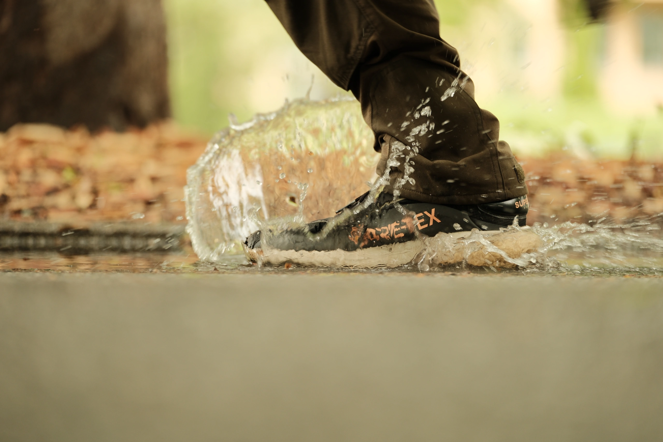 Boot crushing a clear container as water splashes outward