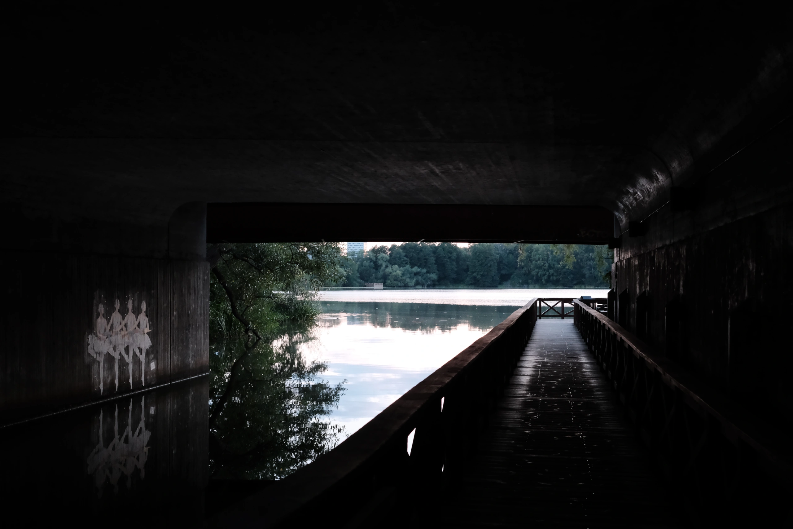 Under the brigde there is a walkway on the one side and a lake on the other.