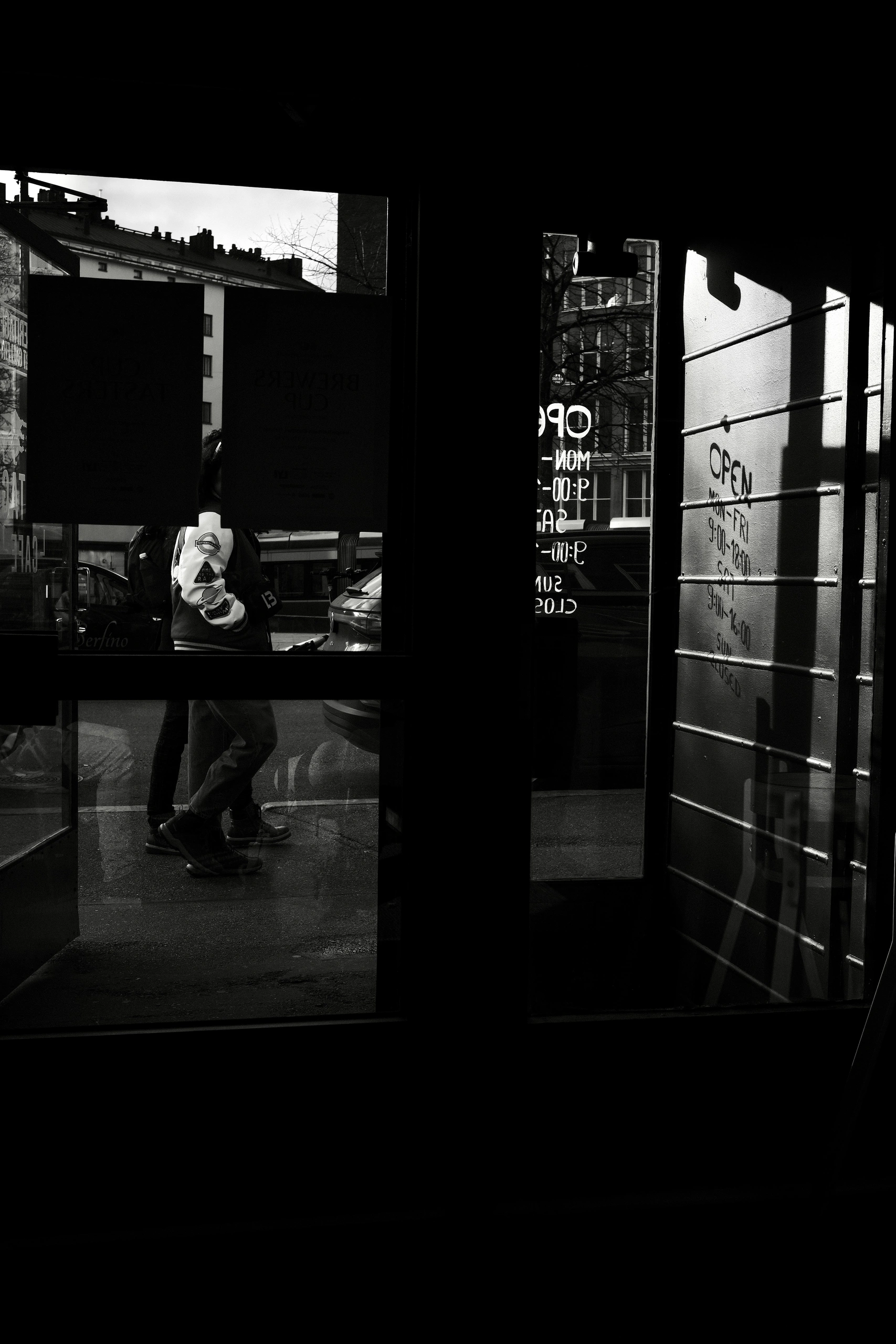 Figure seen through reflections in a dark glass doorway