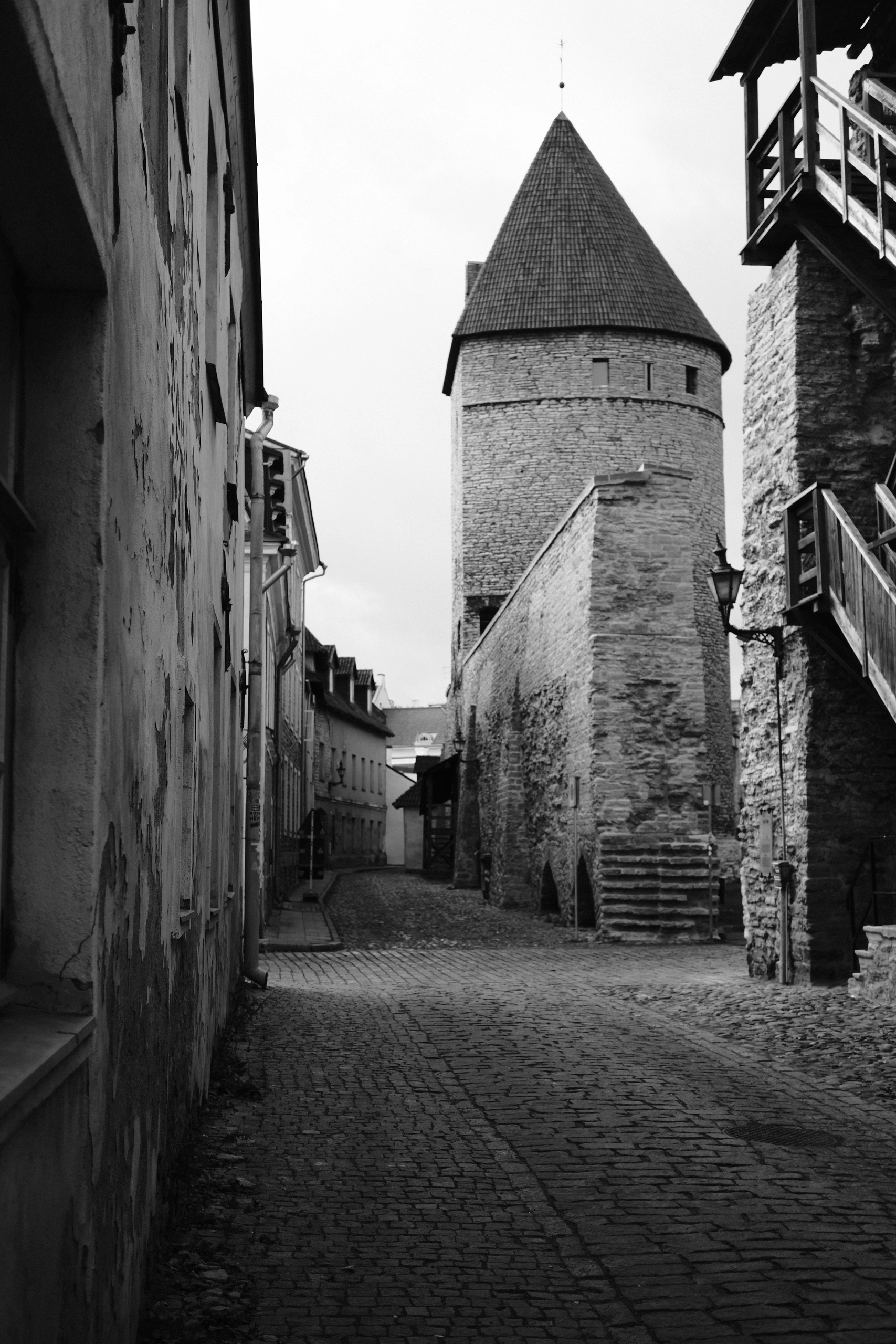 Narrow cobblestone lane ending at a stone tower