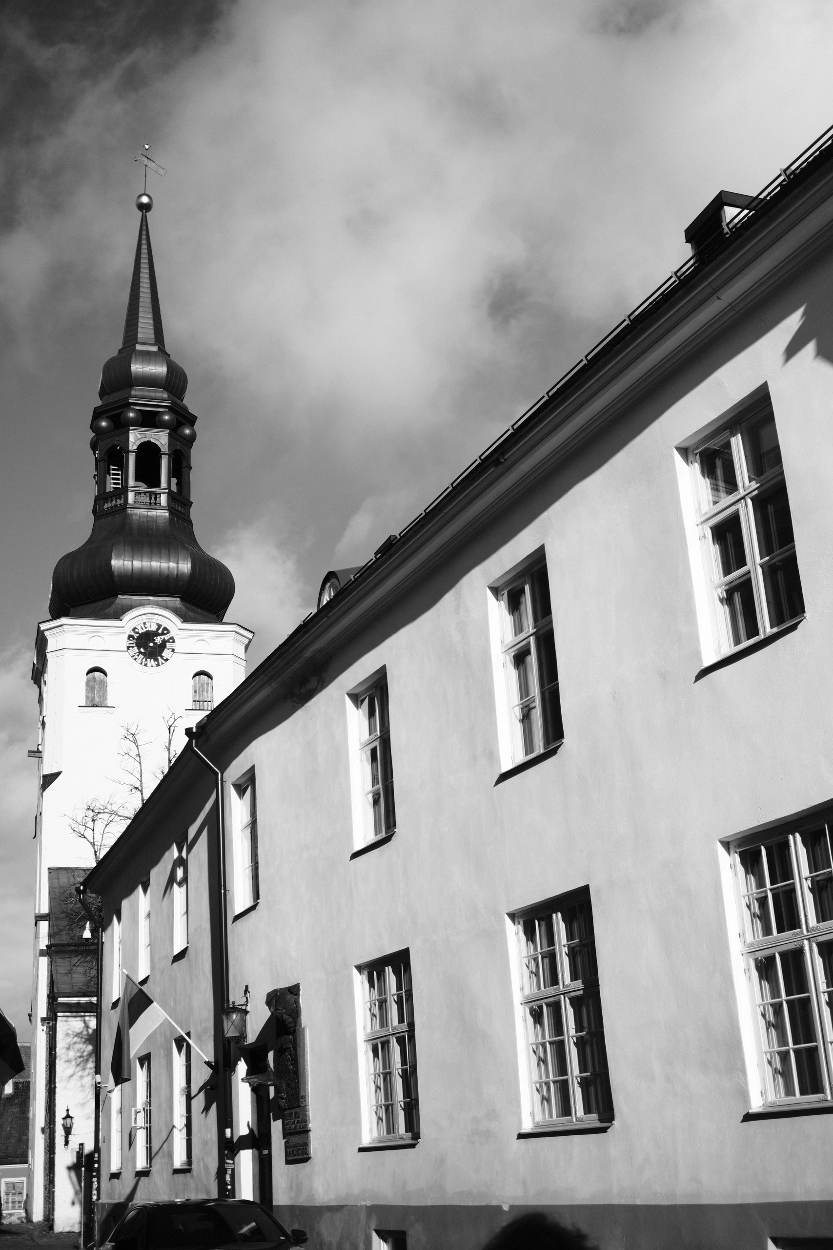 White church facade with a dark spire beneath clouds