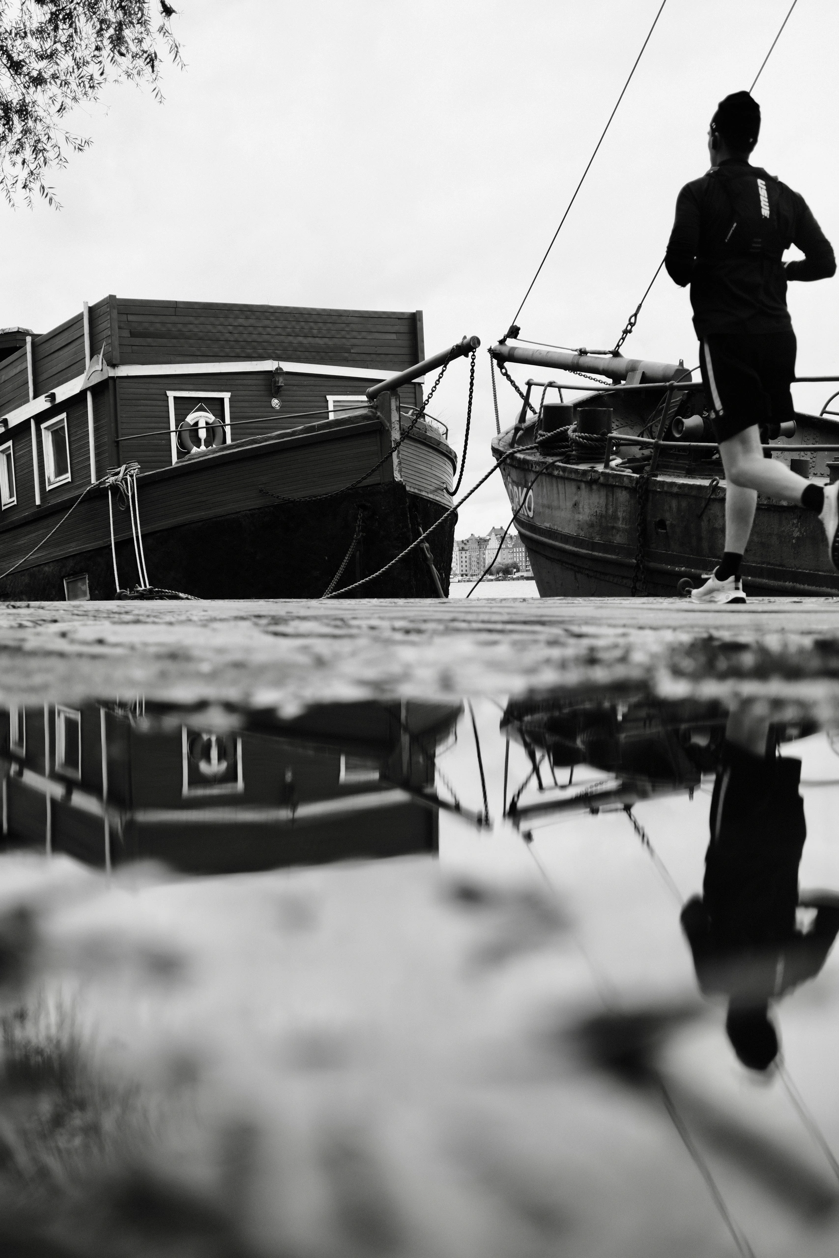 Person beside moored boats reflected in the water